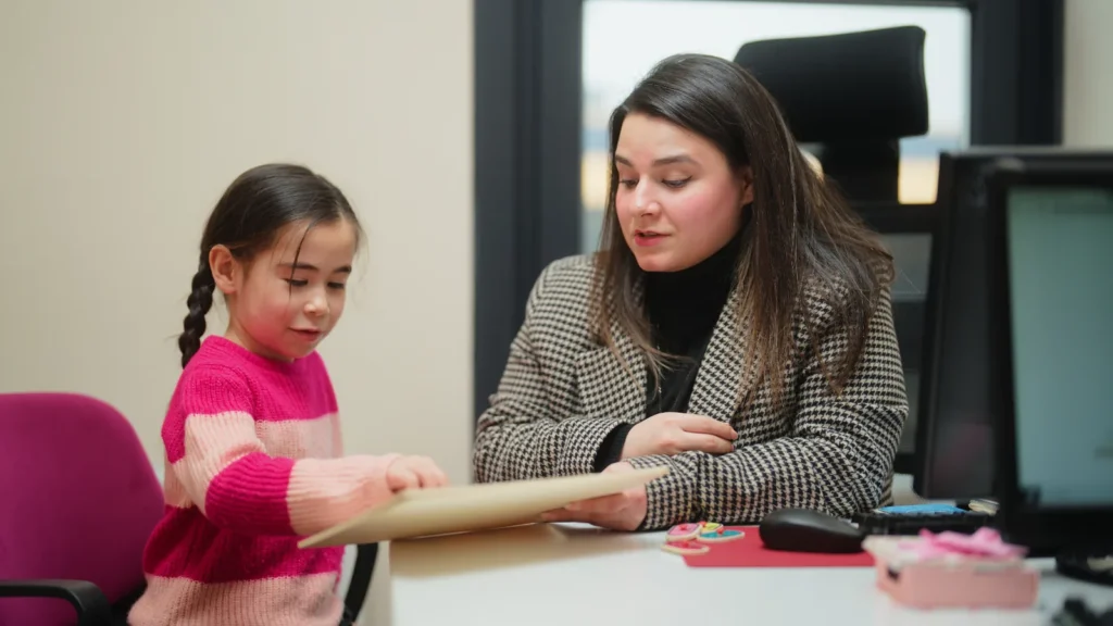 A solicitor sitting with a young child, looking through a drawing together in an office setting.